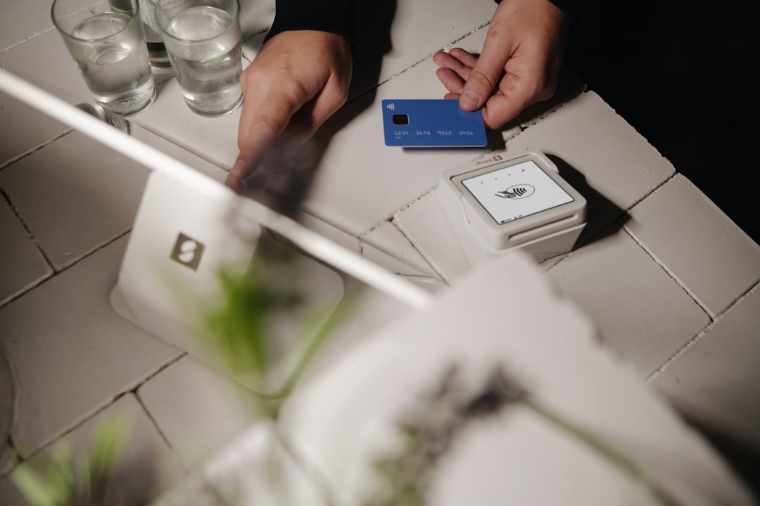 A smooth, wireless payment using a SumUp point of sale system at a small business. The customer effortlessly taps their blue credit card, demonstrating the ease of modern, cashless transactions in a professional environment.